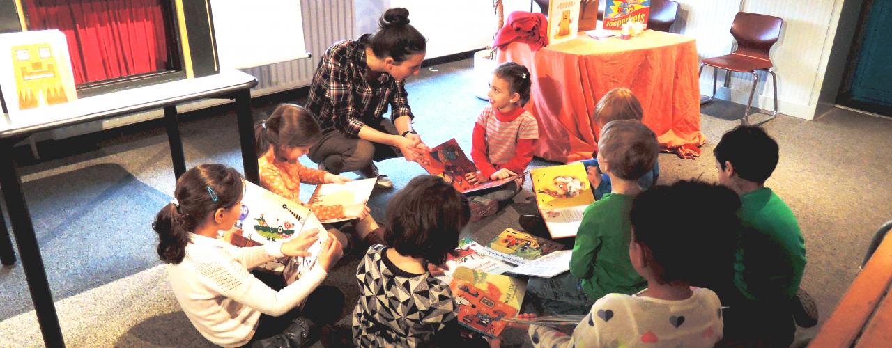 Een student vertelt een verhaal aan kleuters in een Brusselse bibliotheek. 