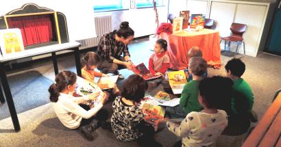 Een student vertelt een verhaal aan kleuters in een Brusselse bibliotheek. 